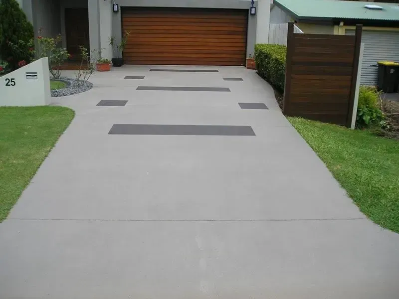 A driveway leading to a house with a wooden garage door — Concrete Colour Solutions in Morisset, NSW