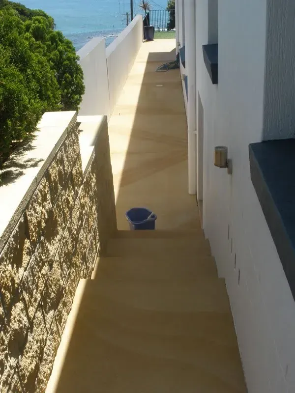 A narrow walkway with a blue bucket on the ground — Concrete Colour Solutions in Morisset, NSW