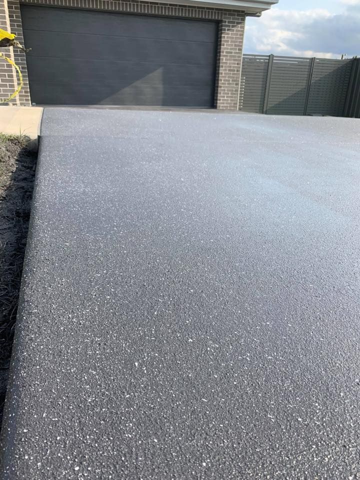A Gray Concrete Driveway with A Garage Door in The Background — Concrete Colour Solutions in Morisset, NSW