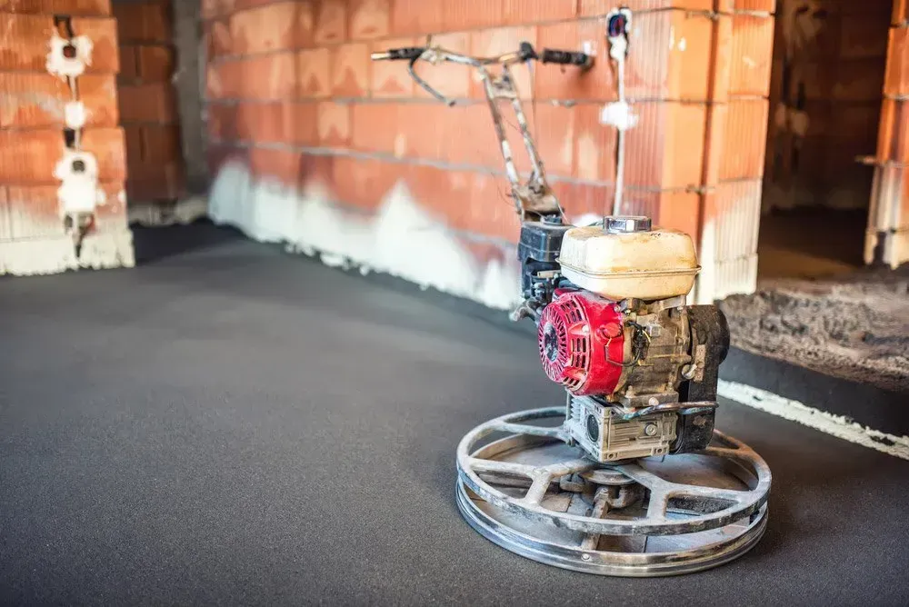 A Machine Is Sitting on The Floor in A Room with A Brick Wall in The Background — Concrete Colour Solutions in Morisset, NSW