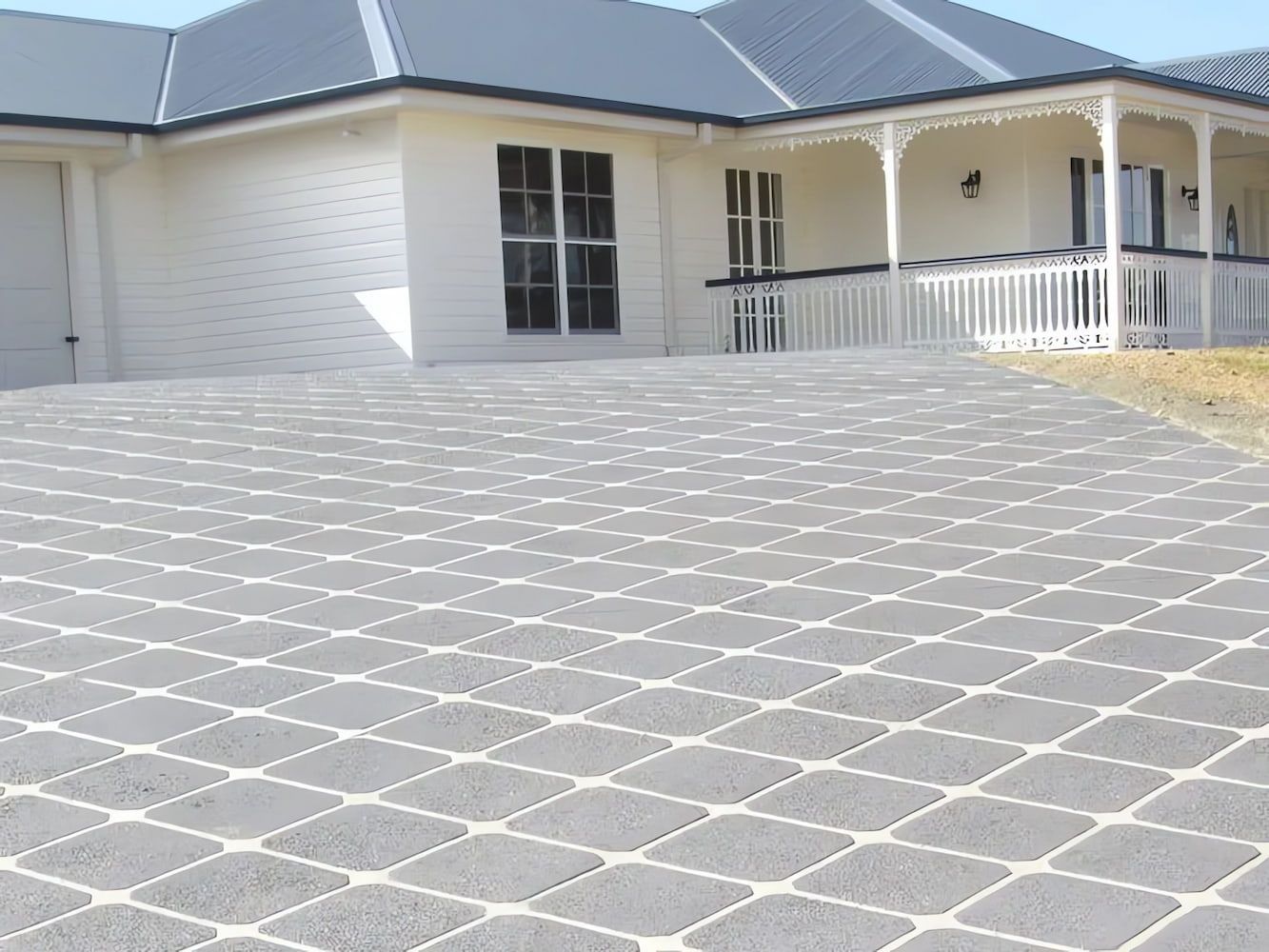 A Large White House with A Large Driveway in Front of It — Concrete Colour Solutions in Morisset, NSW