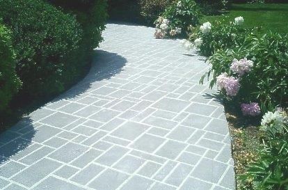 A brick walkway with flowers on the side of it — Concrete Colour Solutions in Morisset, NSW