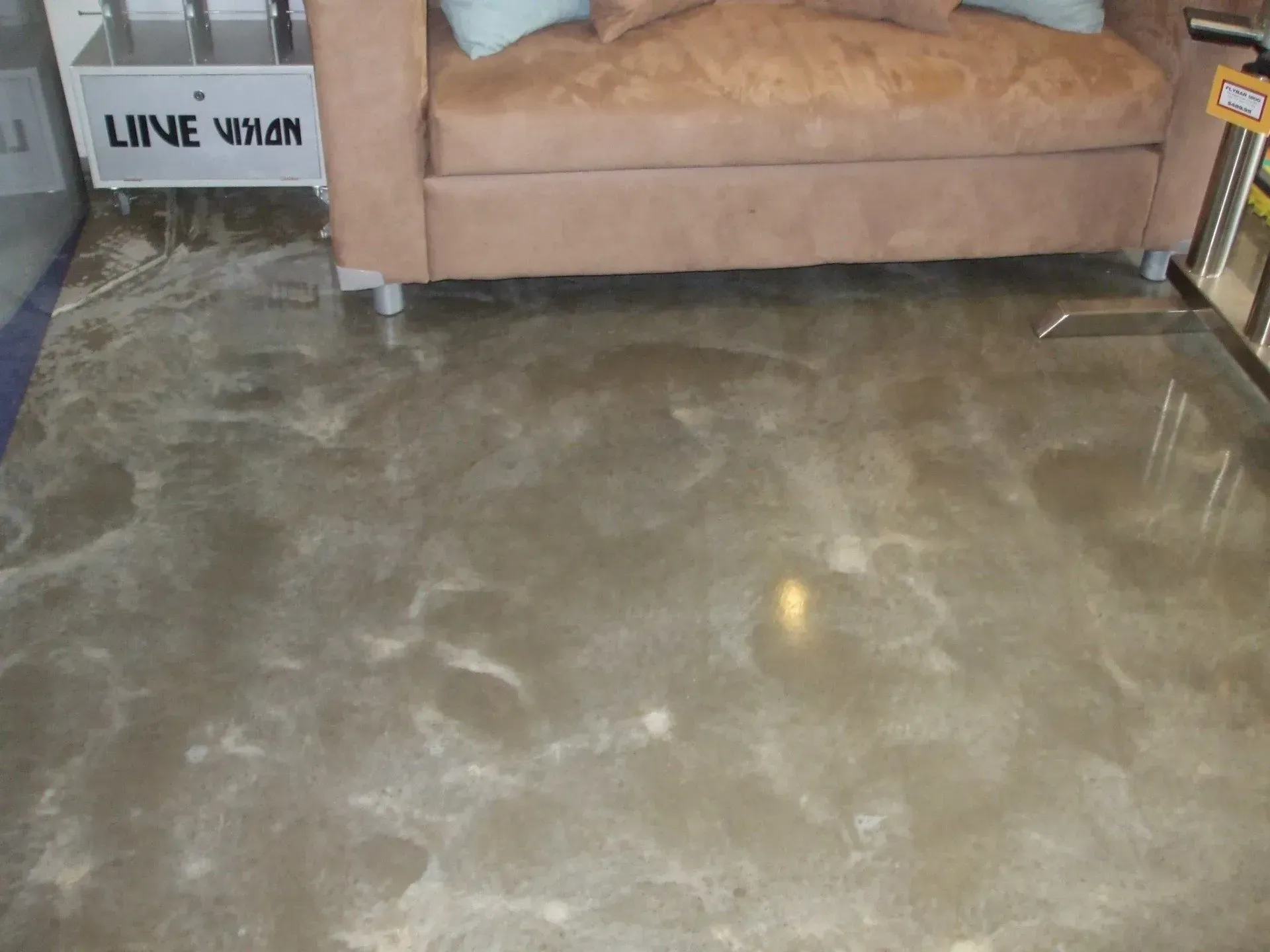 A brown leather couch is sitting on a concrete floor — Concrete Colour Solutions in Morisset, NSW