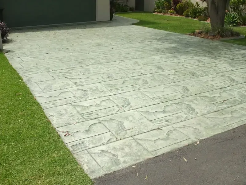 A concrete driveway with a grassy lawn in front of a house. — Concrete Colour Solutions in Morisset, NSW