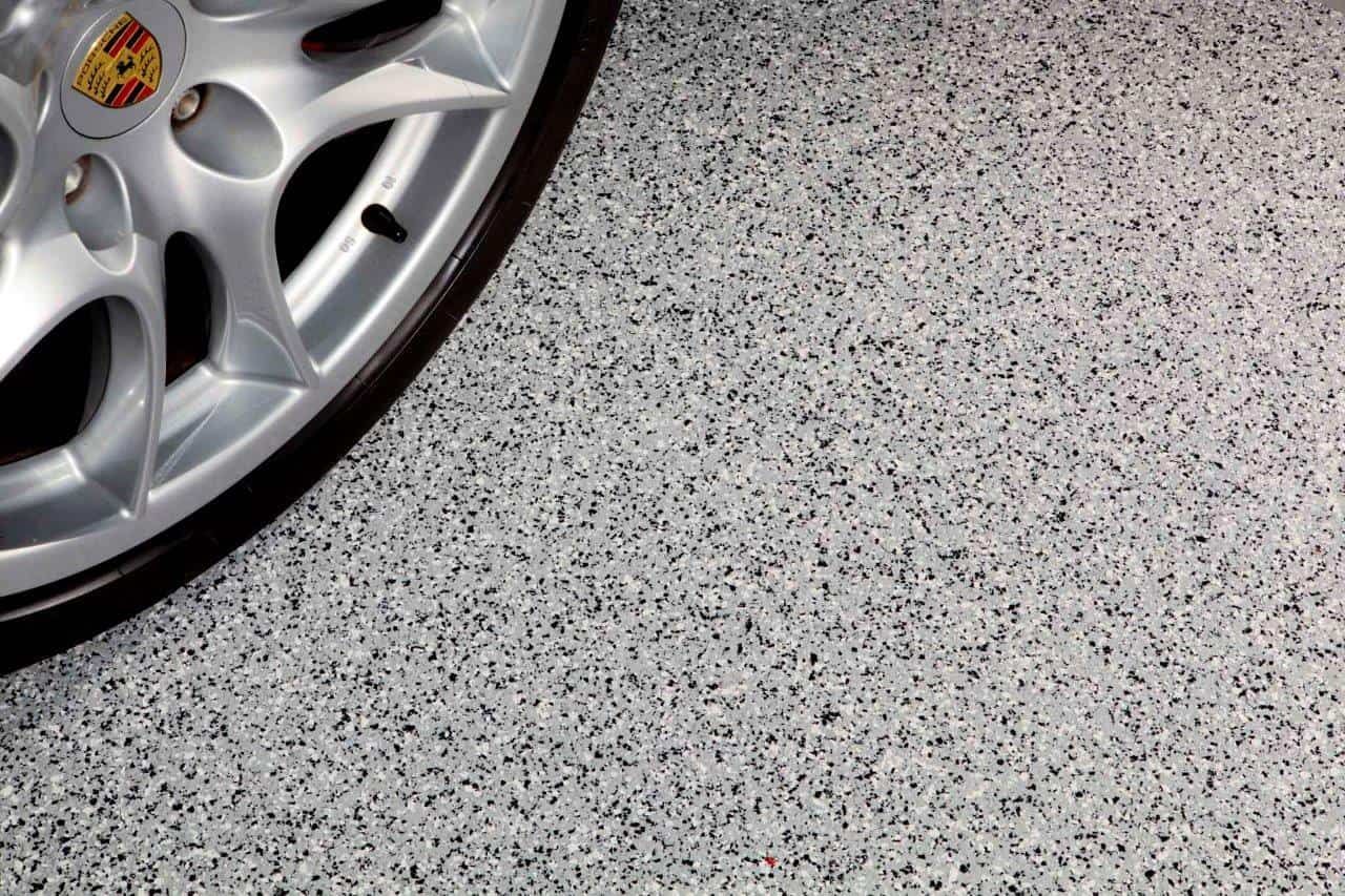 A car wheel is sitting on a gray concrete floor in a garage. — Concrete Colour Solutions in Morisset, NSW