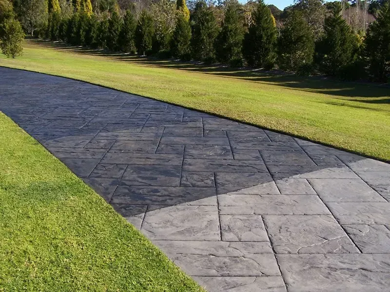 A concrete driveway going through a lush green field — Concrete Colour Solutions in Morisset, NSW
