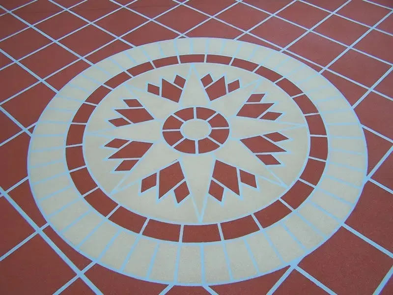 A tiled floor with a circular design in the middle — Concrete Colour Solutions in Morisset, NSW