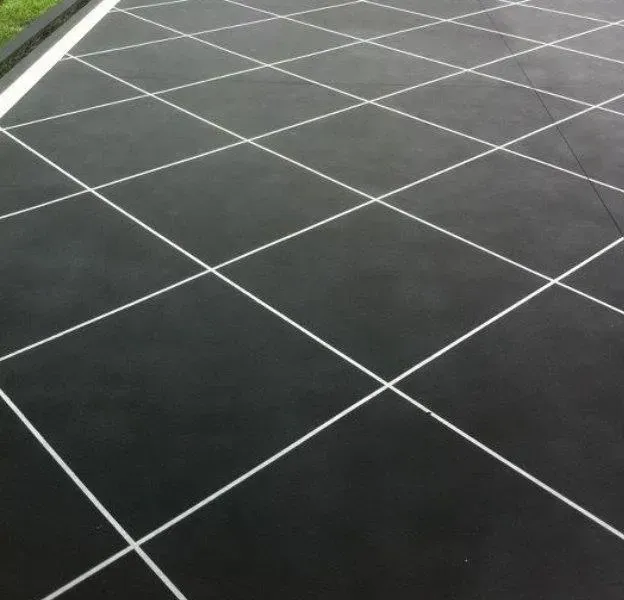 A black tile floor with white lines on it — Concrete Colour Solutions in Morisset, NSW