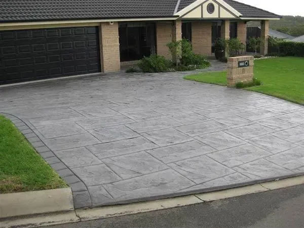 A driveway leading to a house with a black garage door — Concrete Colour Solutions in Morisset, NSW