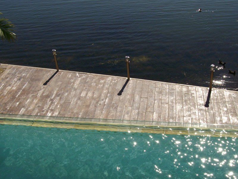 A Wooden Deck With A Pool And Lake Either Side — Concrete Colour Solutions in Morisset, NSW