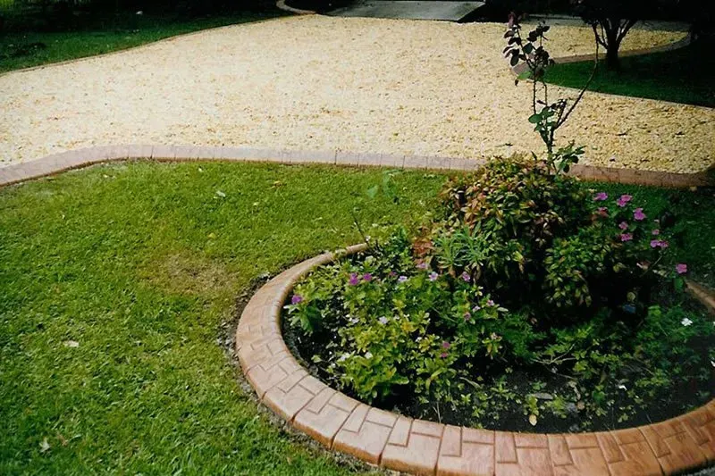 A garden with a brick border and a driveway in the background — Concrete Colour Solutions in Morisset, NSW