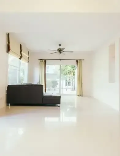 An Empty Living Room with A Black Couch and A Ceiling Fan — Concrete Colour Solutions in Morisset, NSW