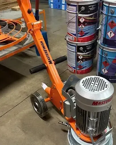 A Machine Is Sitting in A Warehouse Next to Buckets of Paint — Concrete Colour Solutions in Morisset, NSW