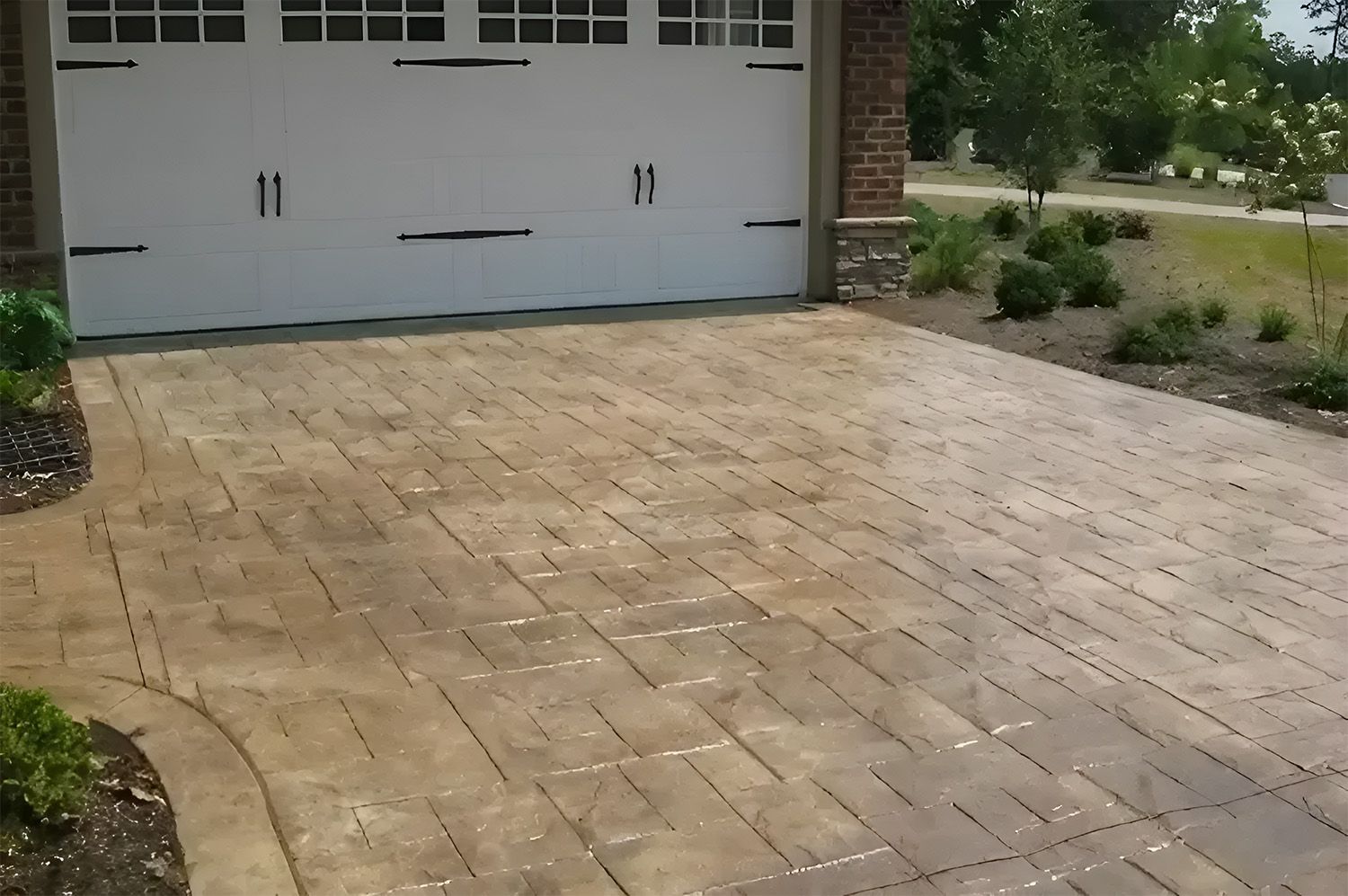 Stamped Concrete Driveway In A Brick Pattern Leading To A White Garage Door