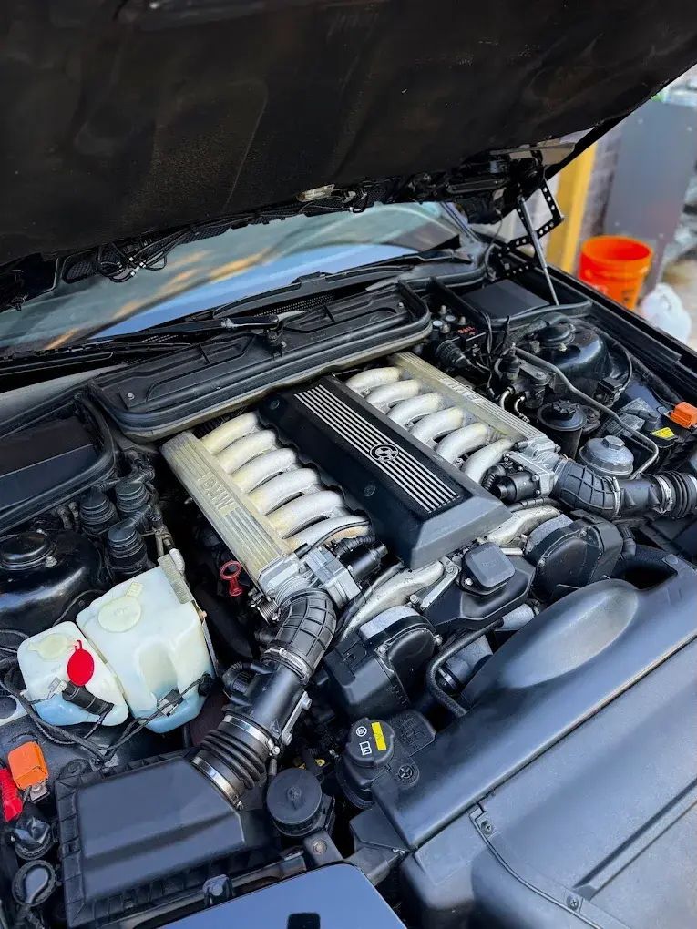 Black BMW V12 engine with open hood; engine bay is clean and detailed. | Friendly Automotive