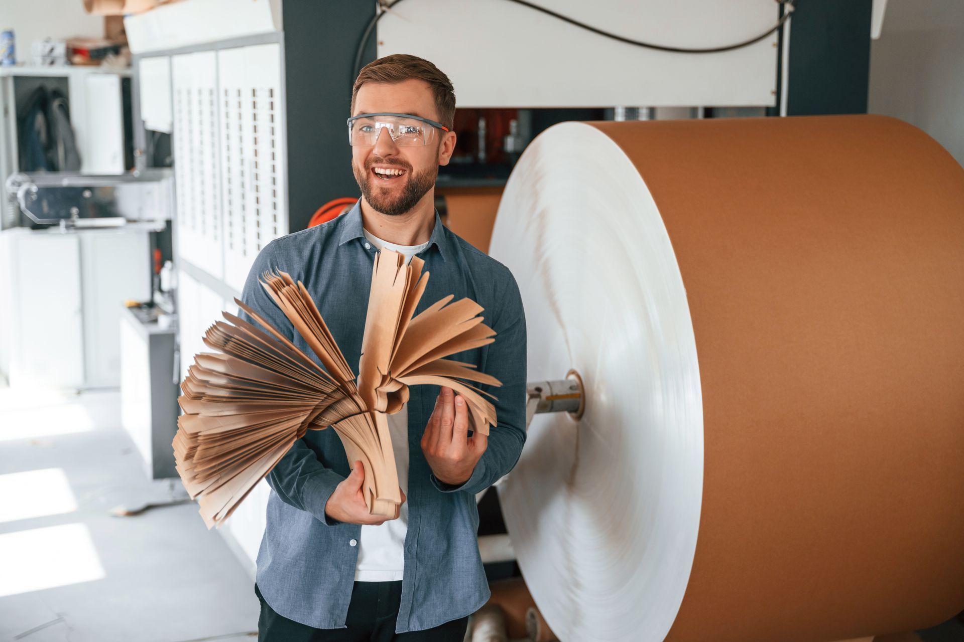 A man is holding a piece of paper in front of a large roll of paper.
