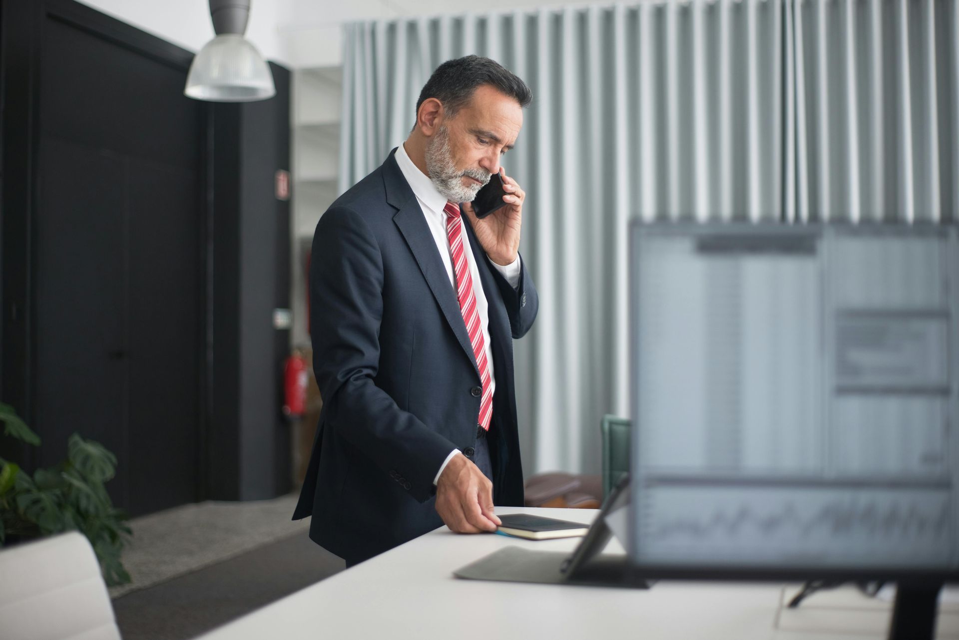 Manufacturing executive in business suit making important phone call in a modern industrial office.