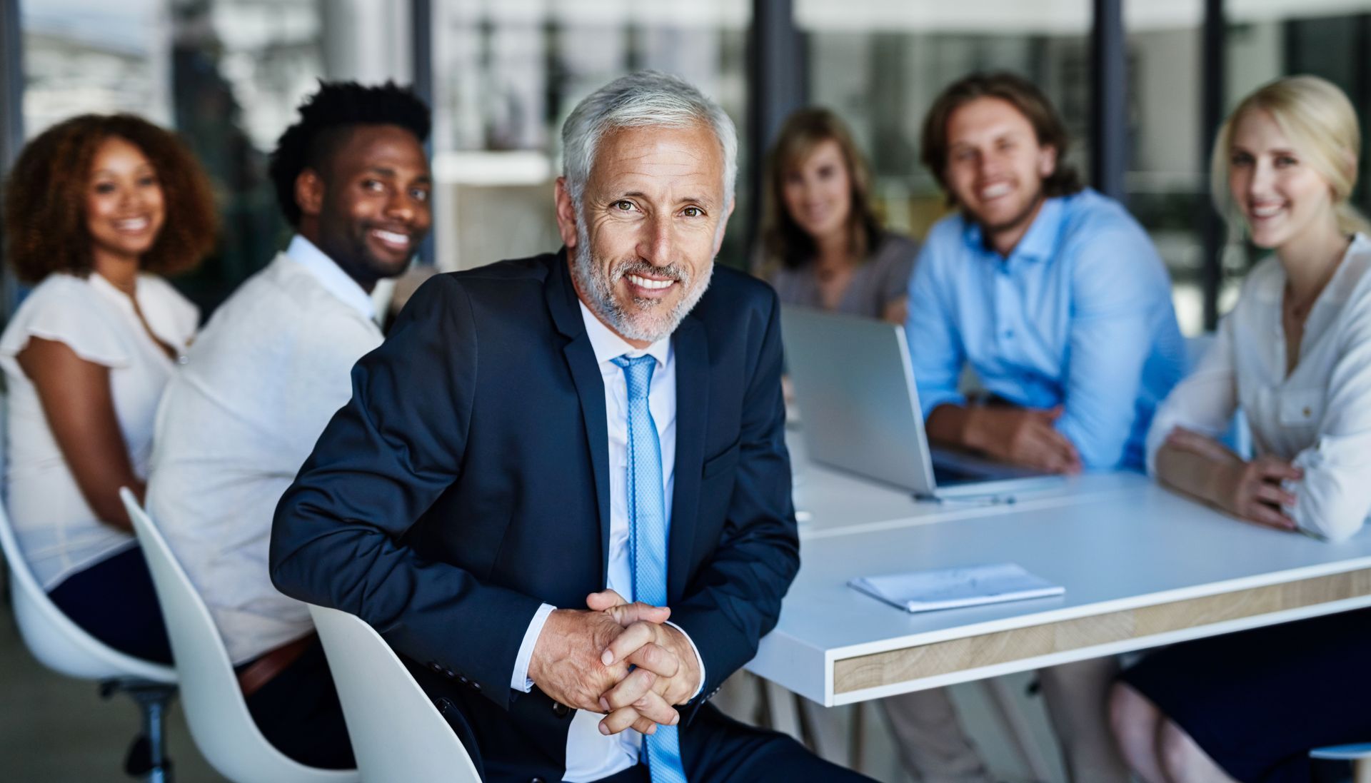 A man in a suit and tie is sitting at a table with a group of people.