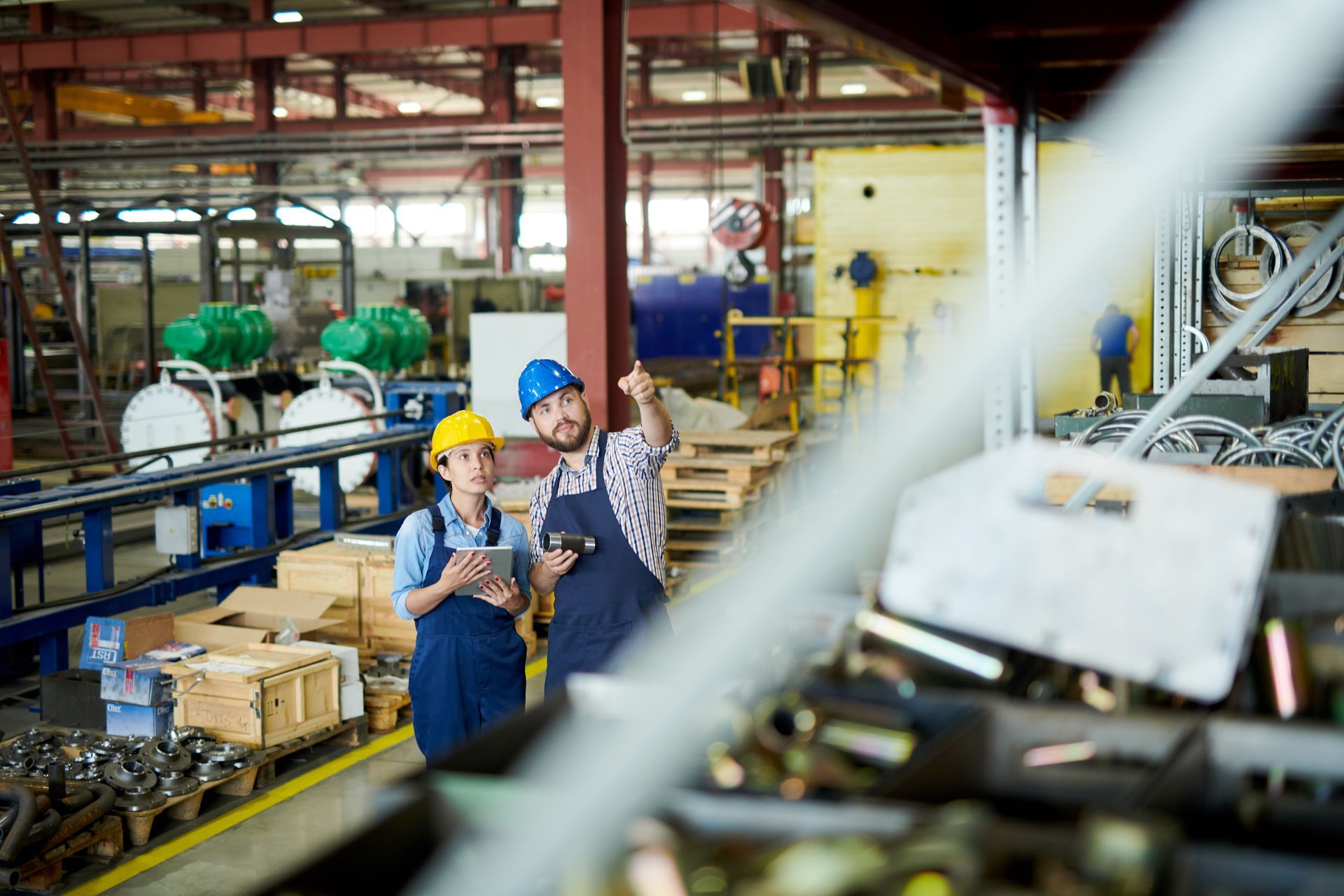 A man and a woman are standing in a factory looking at something.