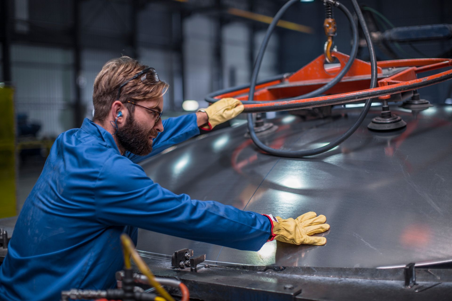 A man is working on a large metal object in a factory.