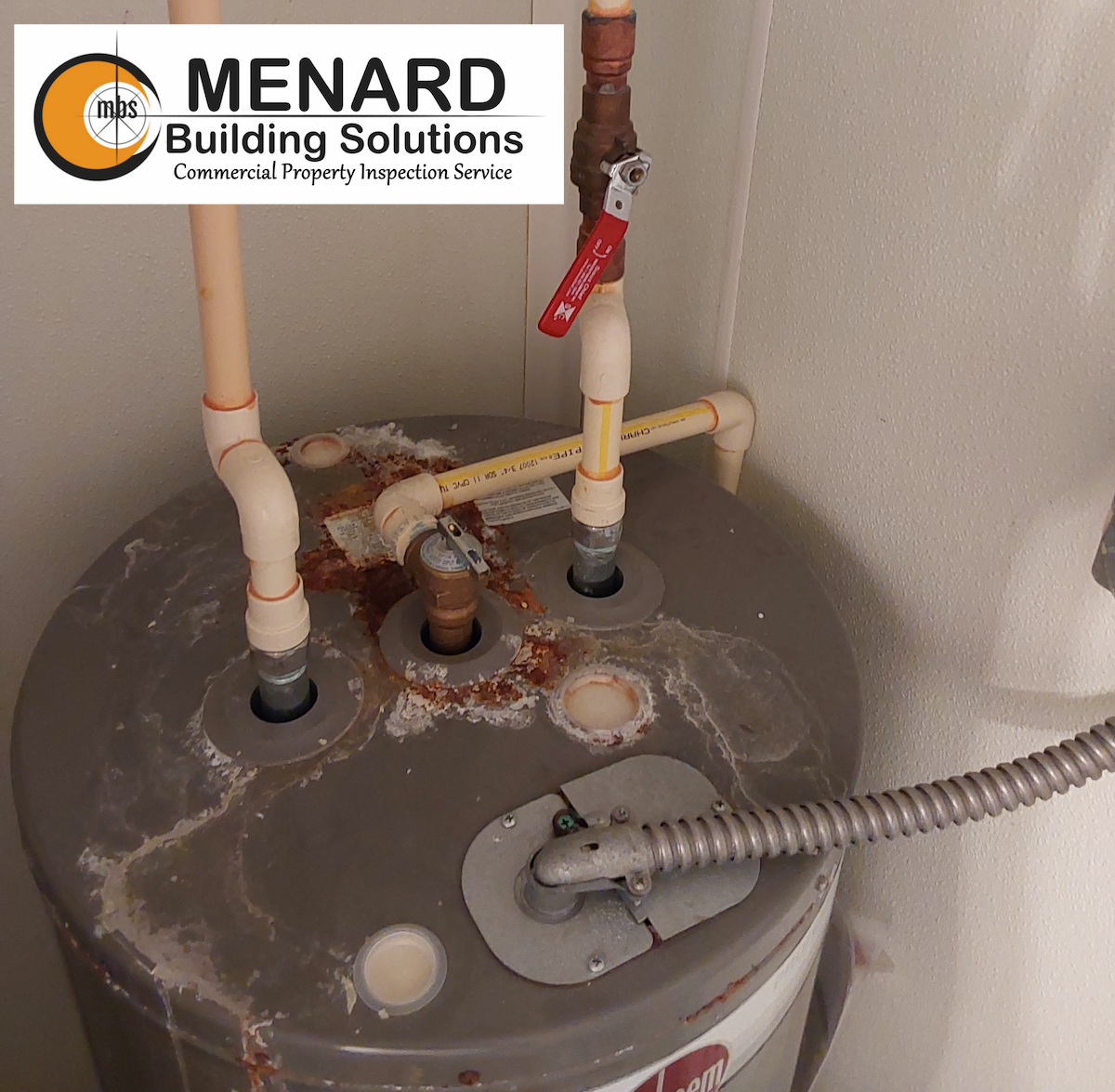 Water heater with rust and corroded fittings; pipes connected to top.