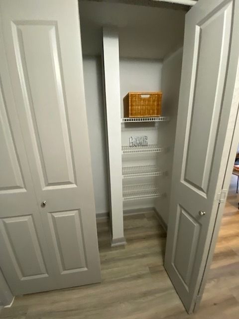 Open closet with white wire shelves and a wicker basket on the top shelf.