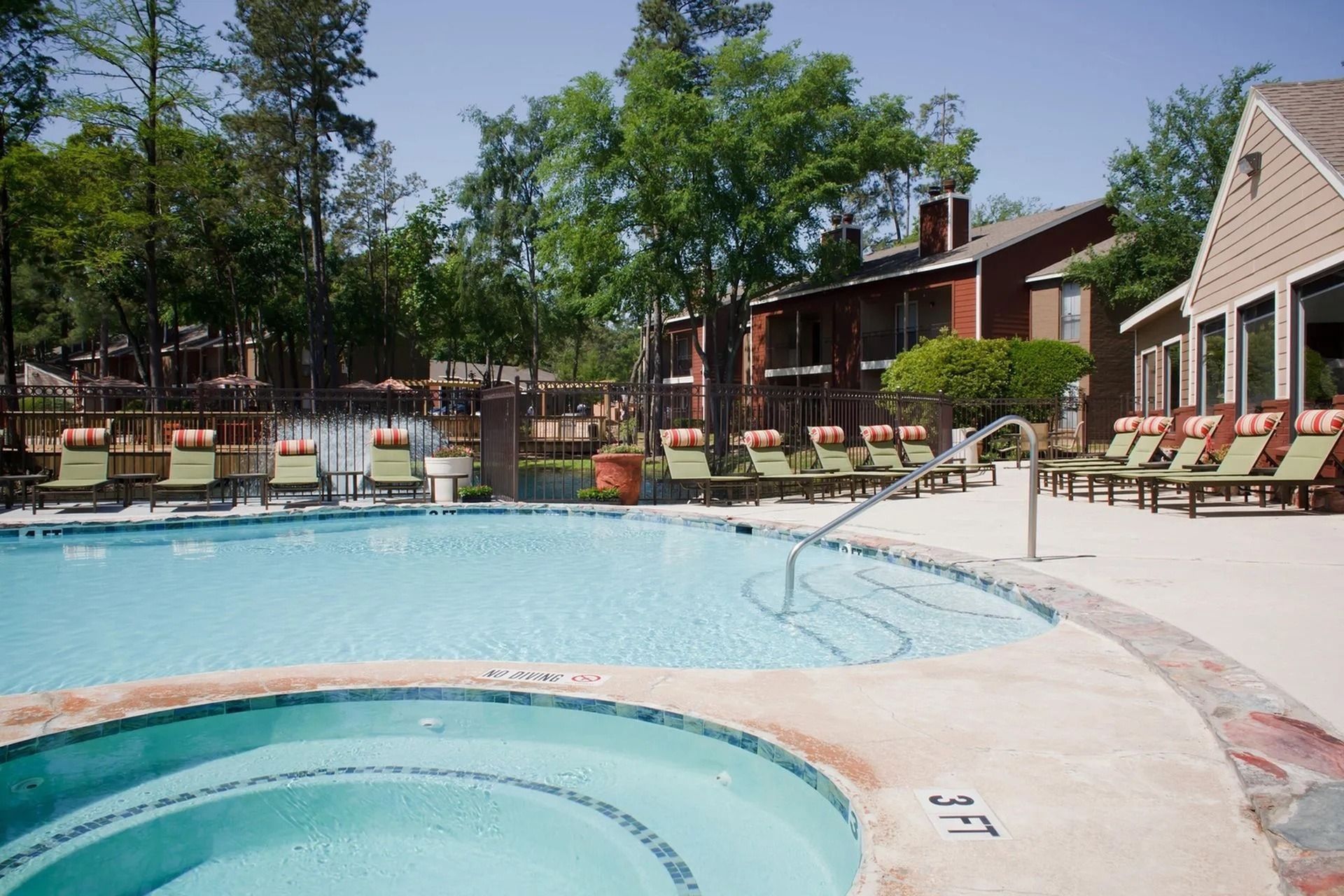 Outdoor community pool with lounge chairs and surrounding apartment buildings