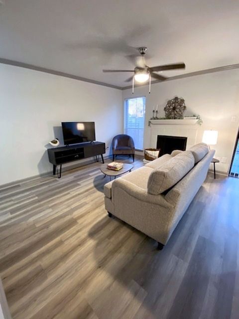Living room with beige sofa, fireplace, TV, and ceiling fan.