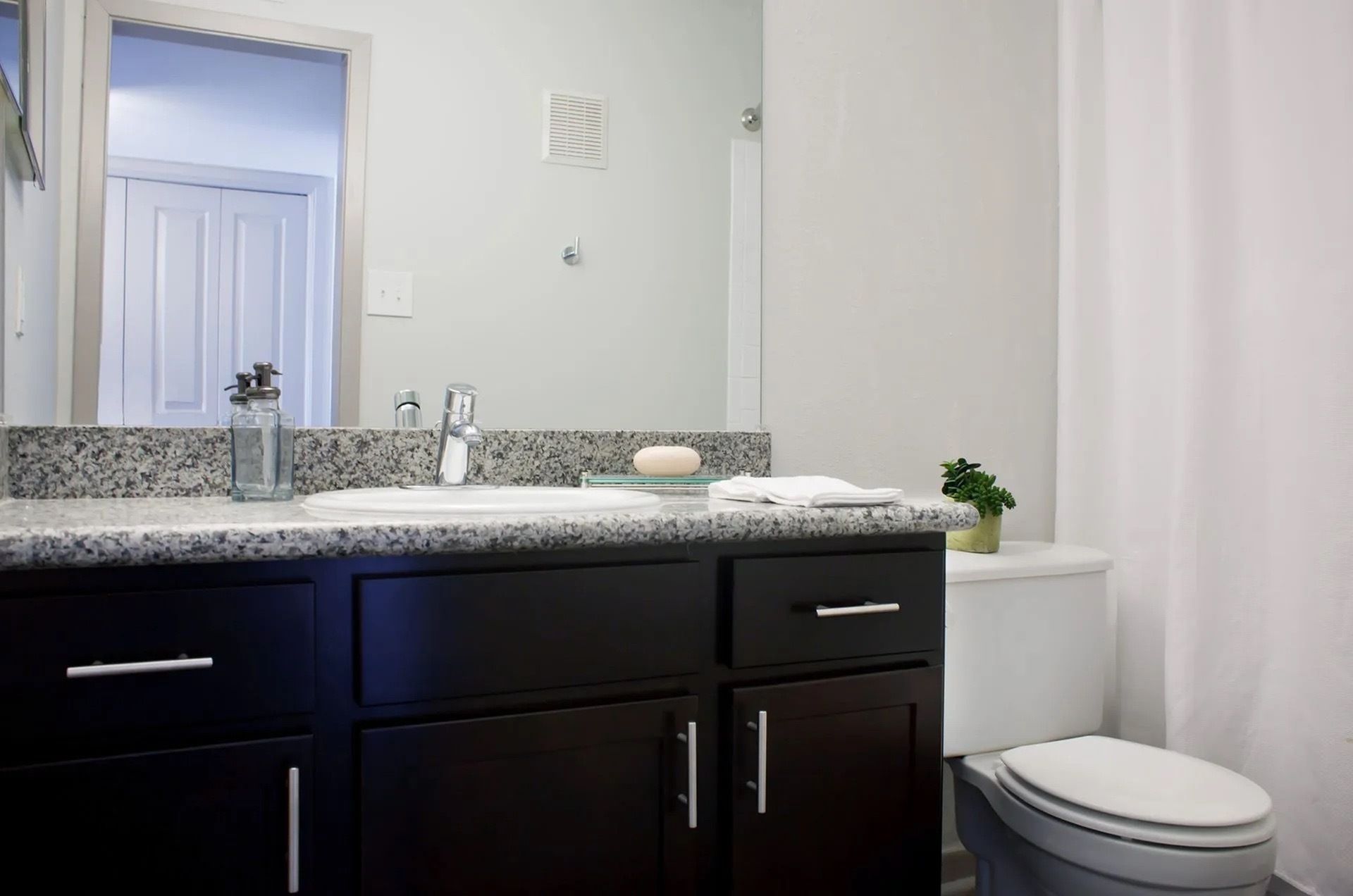 Bathroom vanity with granite countertop, sink, faucet, and toilet.