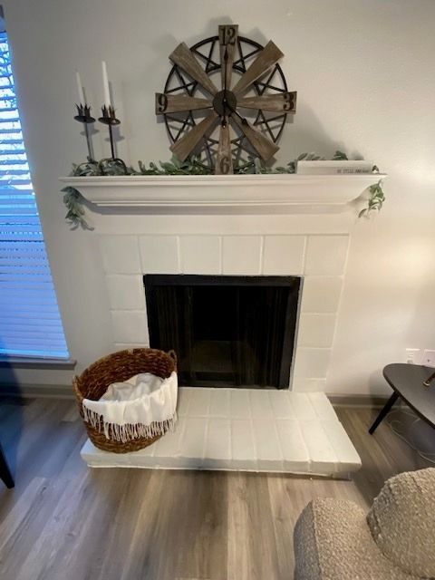 White brick fireplace with a wooden mantel and decorative accents in a living room.