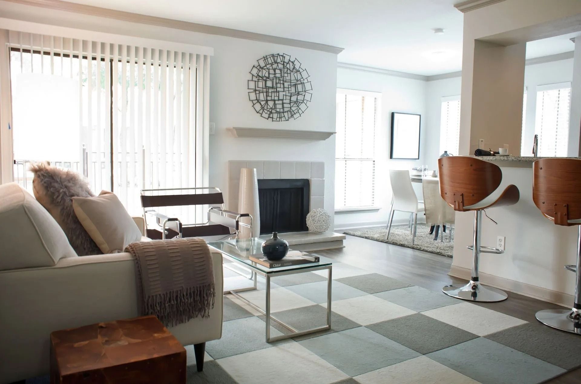 Bright living room in a modern apartment with a fireplace, glass coffee table, and bar seating.