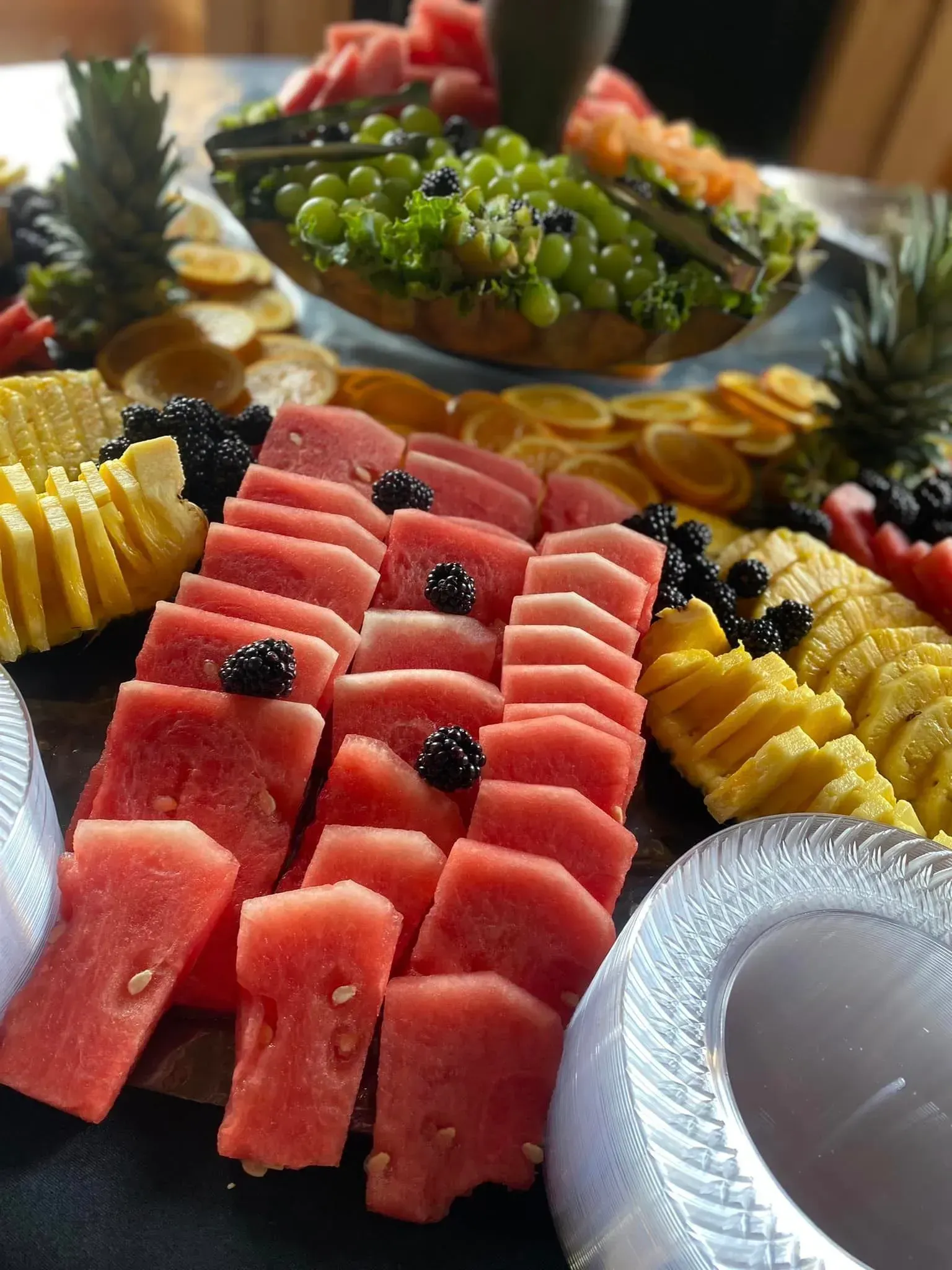 Assorted fruit platter with watermelon, pineapple, grapes, and berries arranged on a table