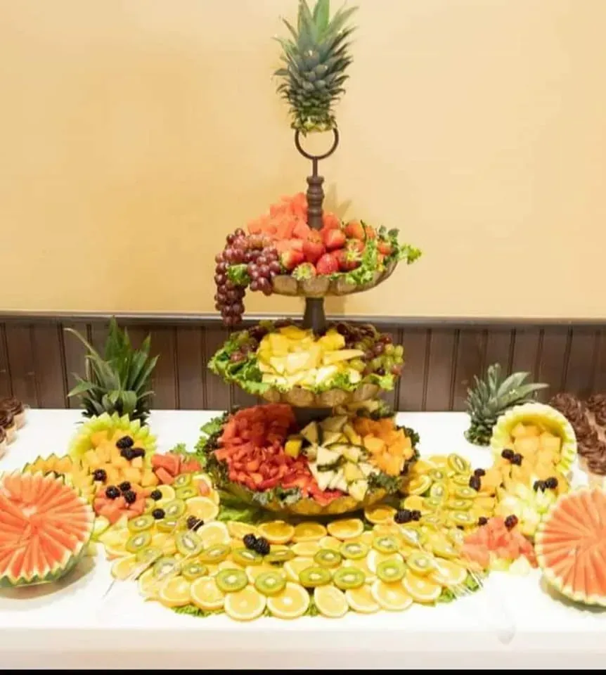 Fruit and flower arrangement centerpiece with pineapple topper and sliced citrus on a table