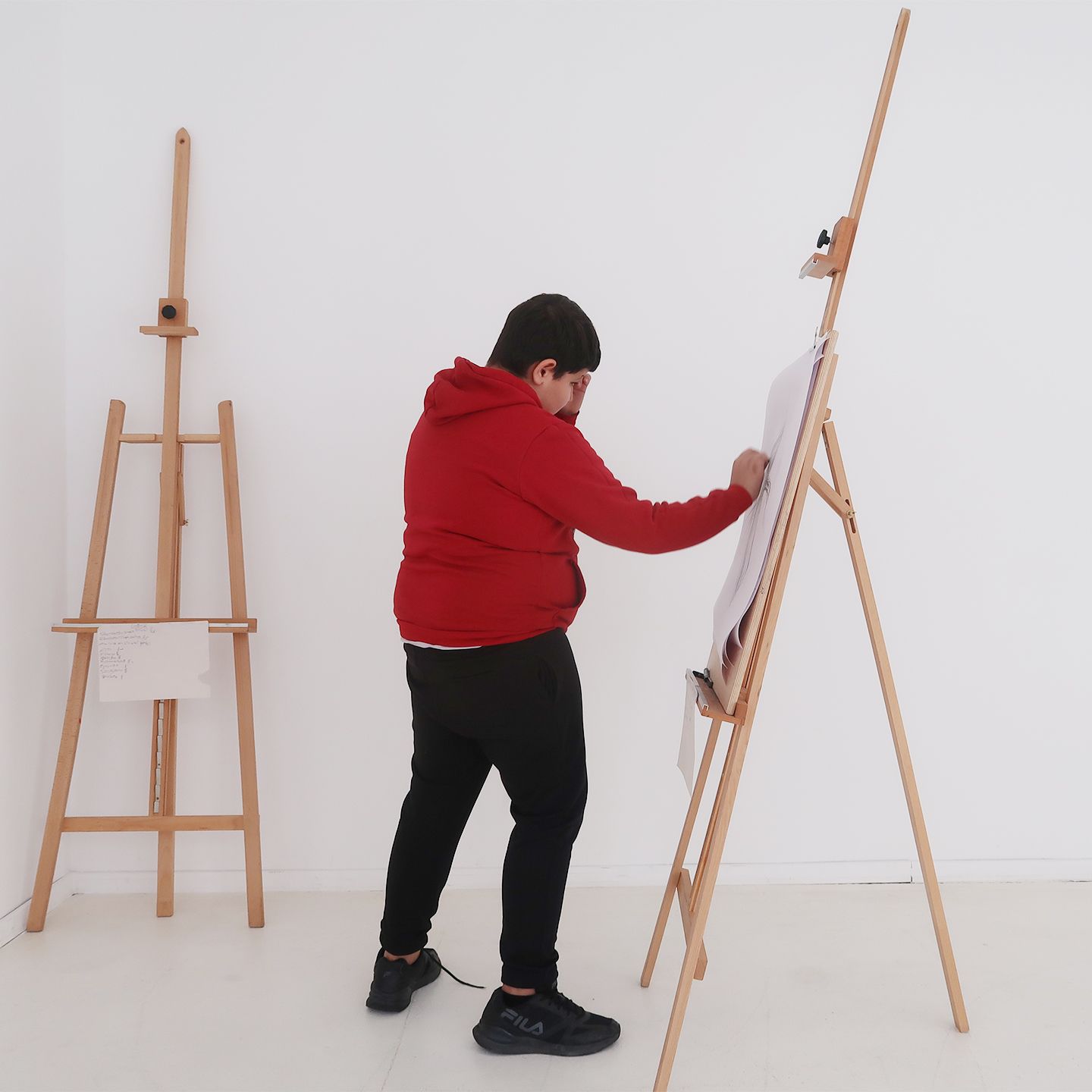 Boy engaging with his artwork on easel.