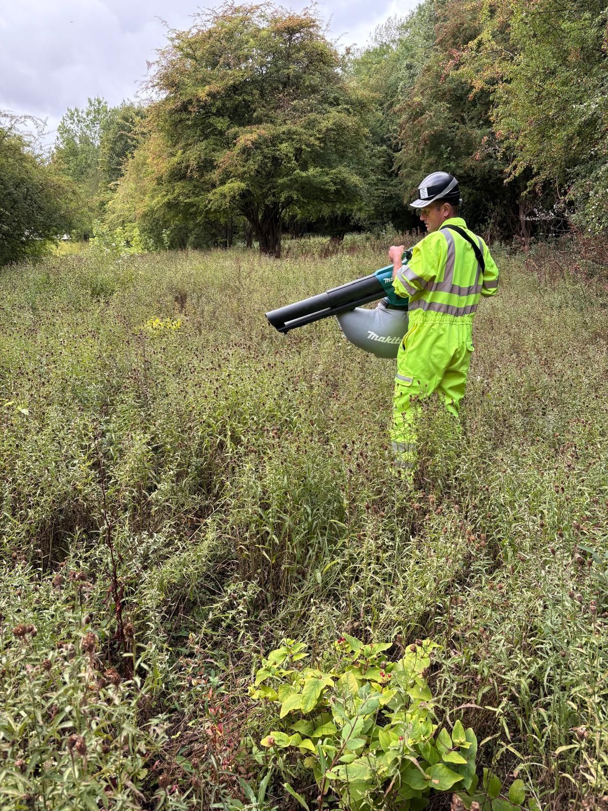 Two workers loading materials into a trailer at a construction site near wind turbines