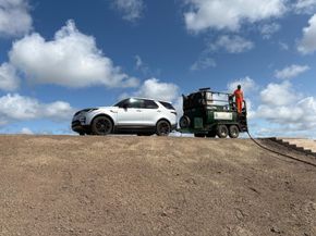 CDTS North & West towed hydroseeder with operator spraying sea defence embankments at Rhyl, North Wales