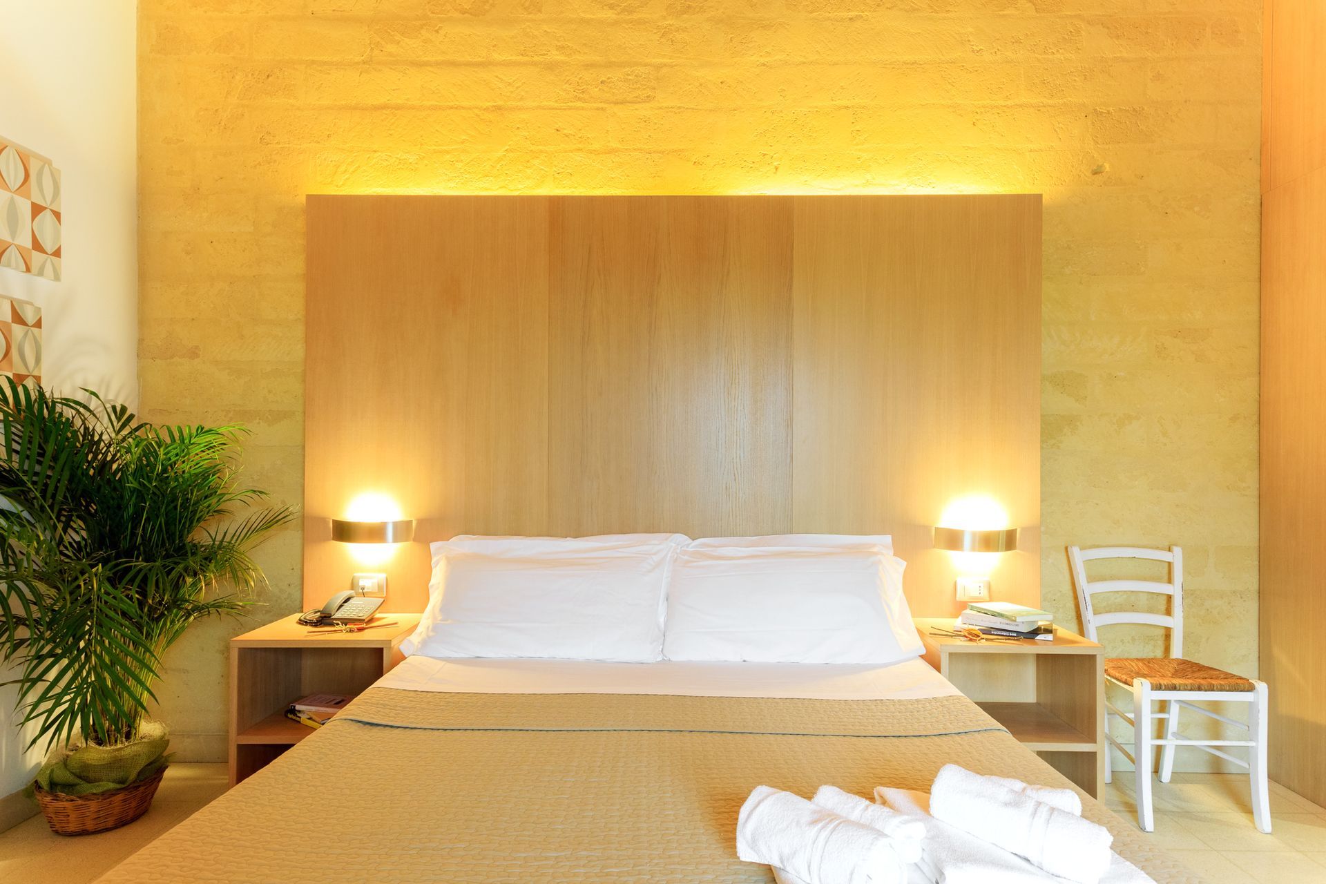 Camera da letto moderna e accogliente con un grande letto, testiera in legno e lampade da comodino.