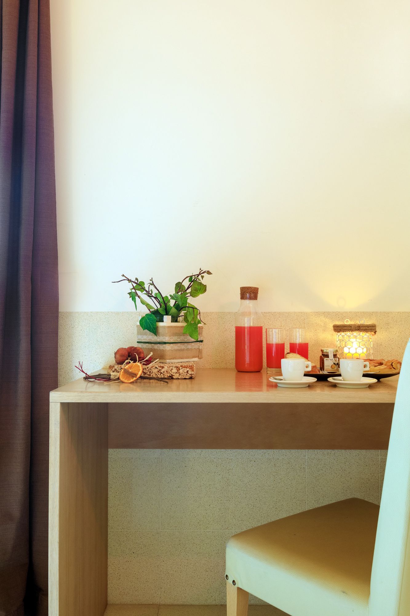 Accogliente tavolo da trucco con fiori, candele e luce calda di una lampada accanto a una sedia.