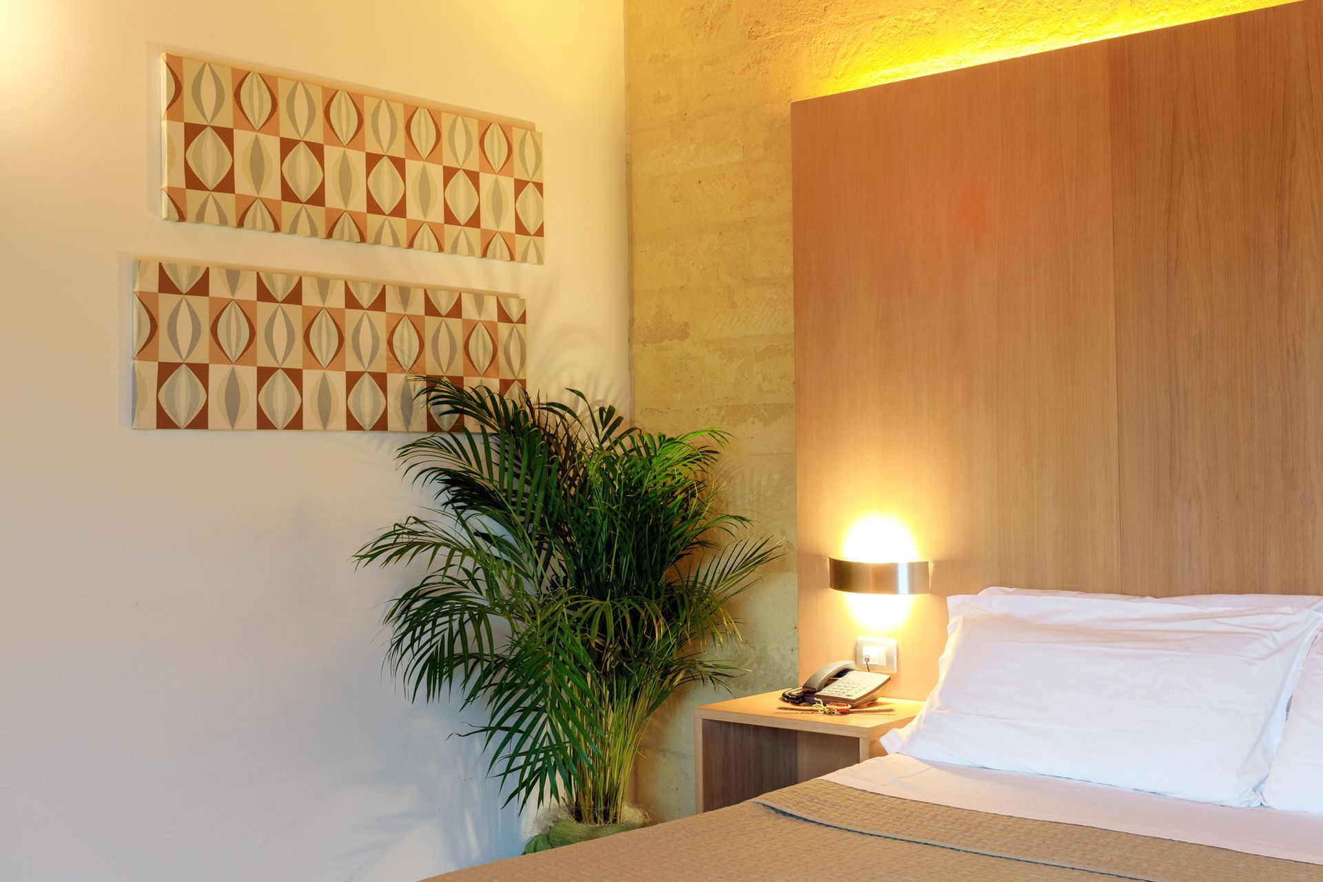 Camera da letto accogliente con testiera in legno, biancheria da letto bianca, lampada da comodino.