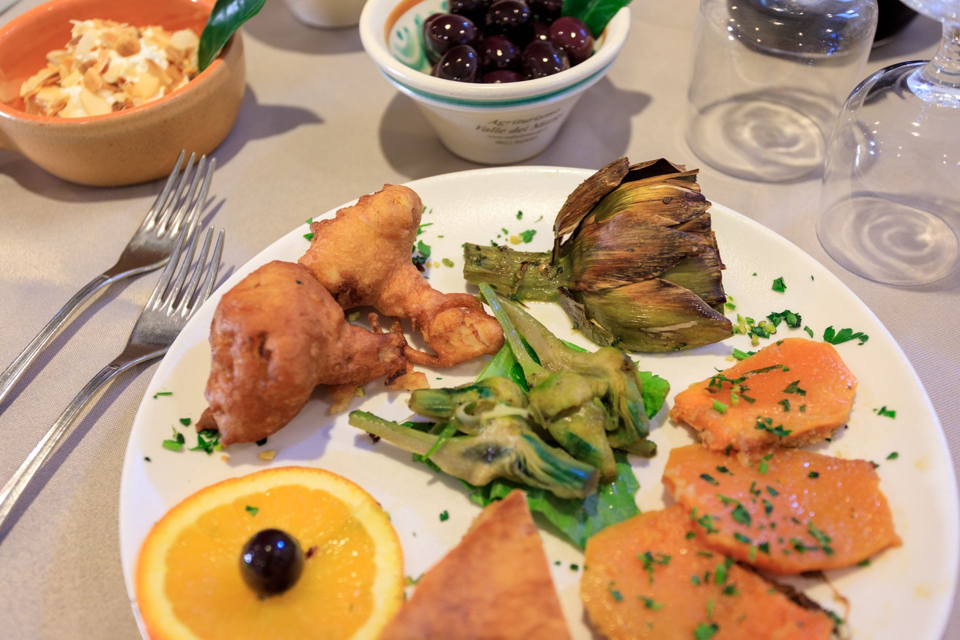 Piatto di antipasti misti con salmone, fritture, verdure e olive su un tavolo da pranzo