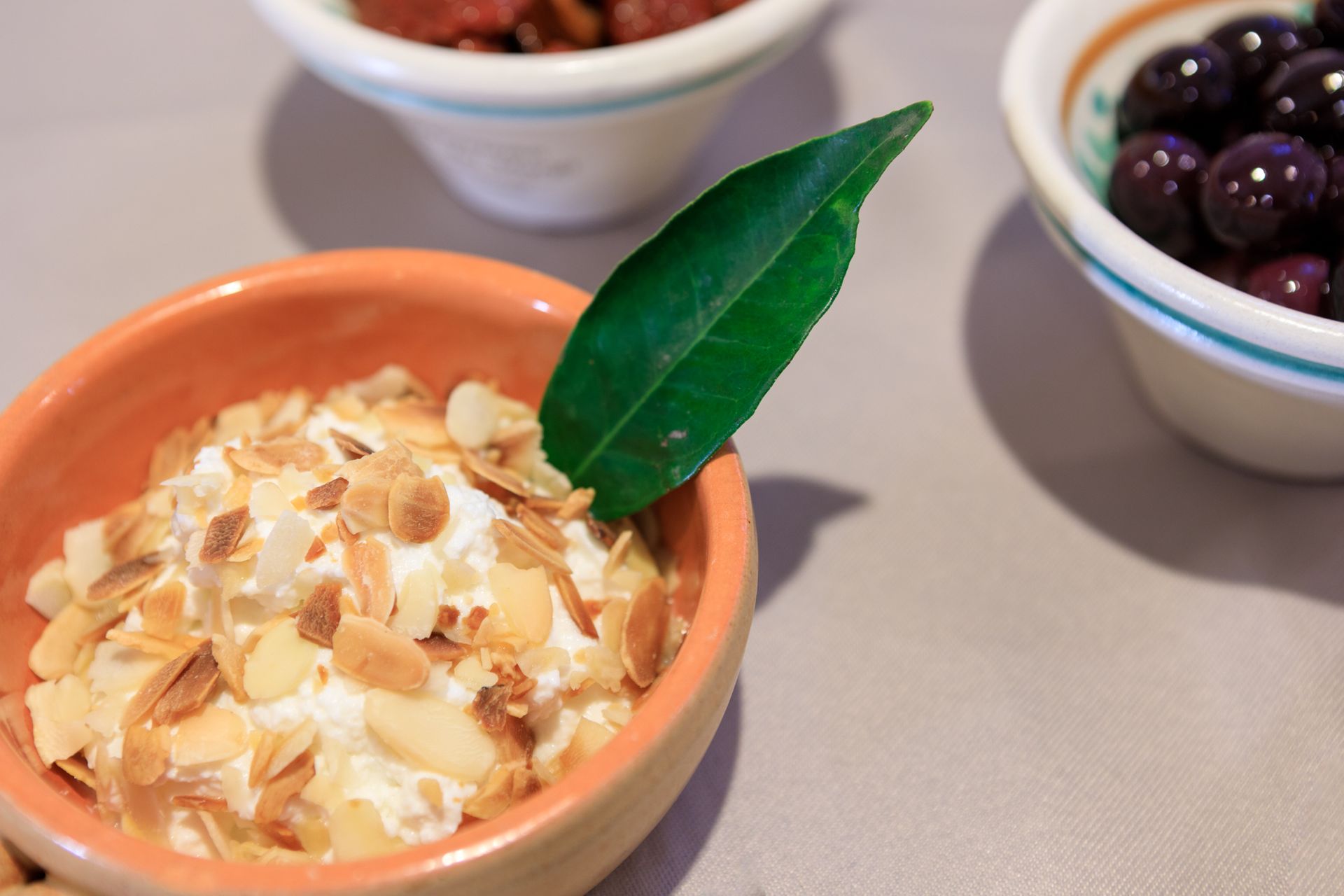 Piccola ciotola di terracotta con cocco e mandorle, guarnita con una foglia verde, su un tavolo