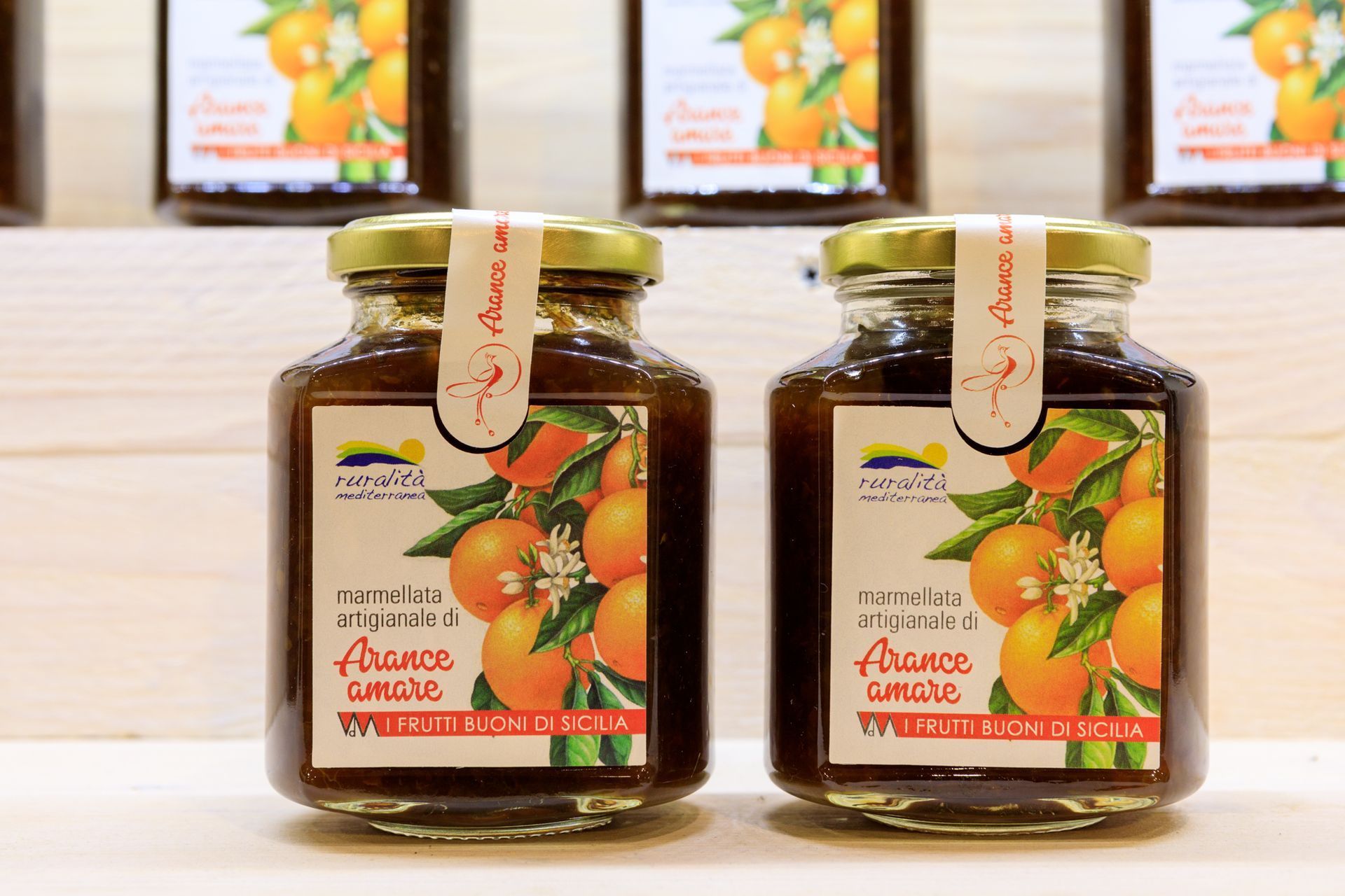 Due vasetti di vetro di marmellata d'arance con etichette di frutta su un tavolo di legno.