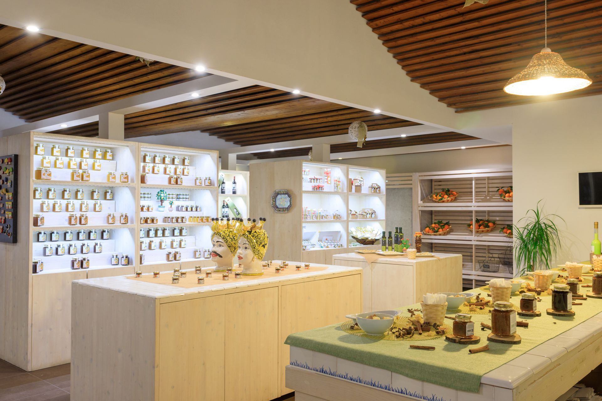 Showroom di cucine moderne con soffitto in legno, mobili bianchi e tavoli espositivi per le stoviglie.