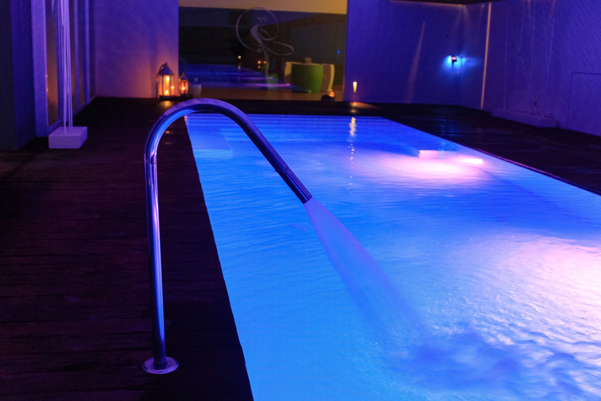 Piscina interna illuminata di blu con corrimano in metallo e acqua increspata