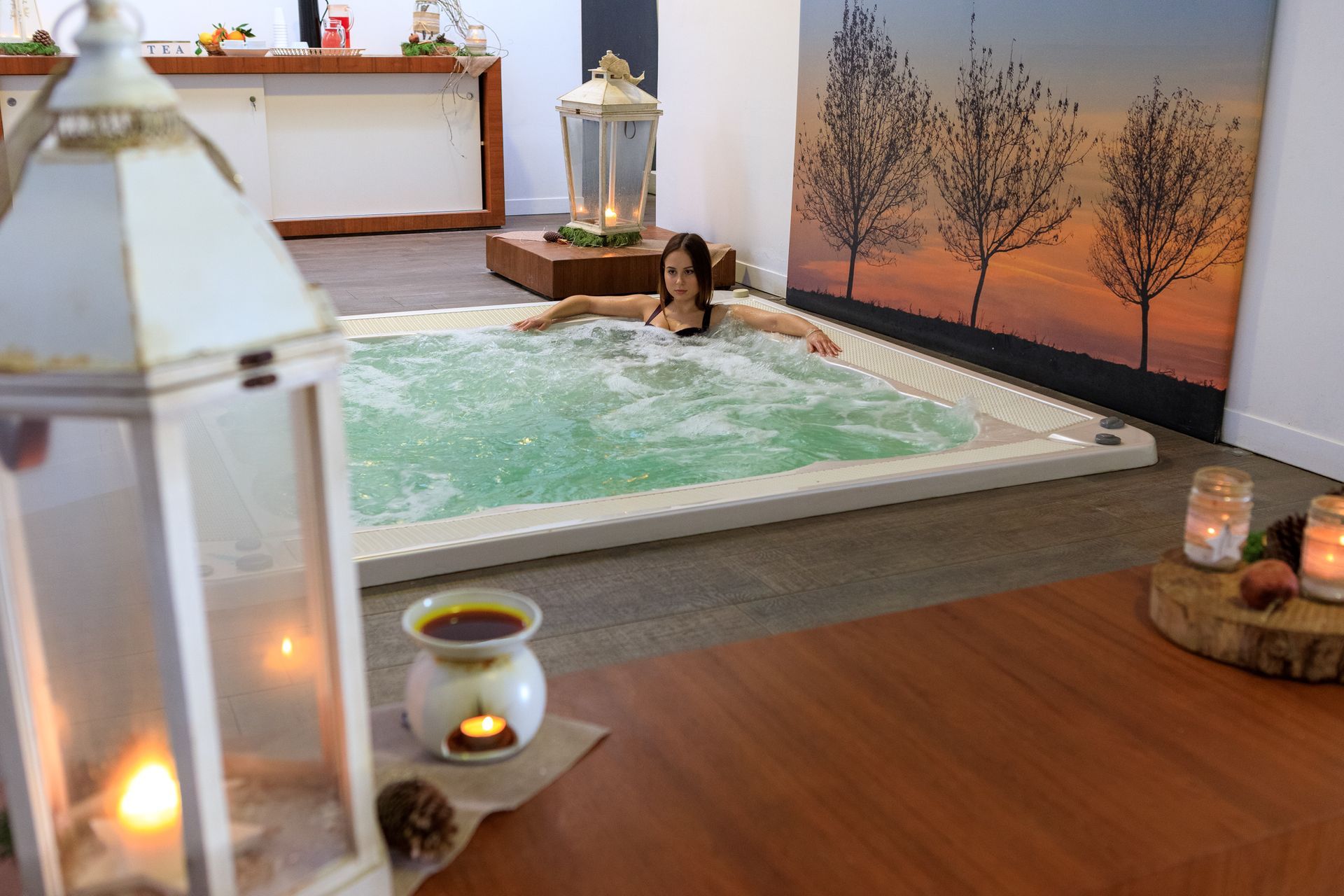 Vasca idromassaggio con una persona immersa nell'acqua frizzante, candele e lanterne in una stanza rilassante