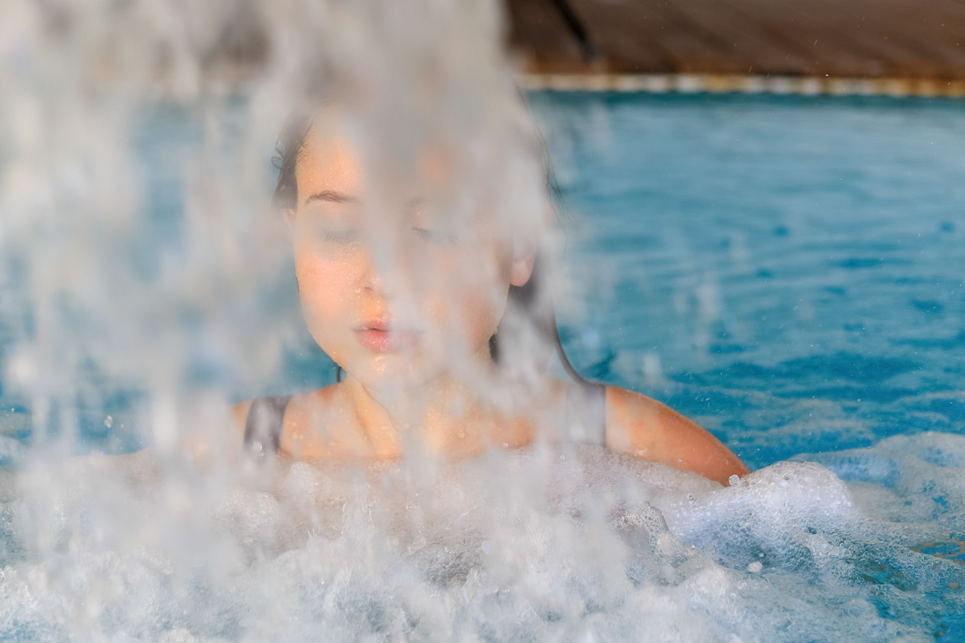 Una persona si rilassa in una piscina gorgogliante, con l'acqua che le schizza sul viso.