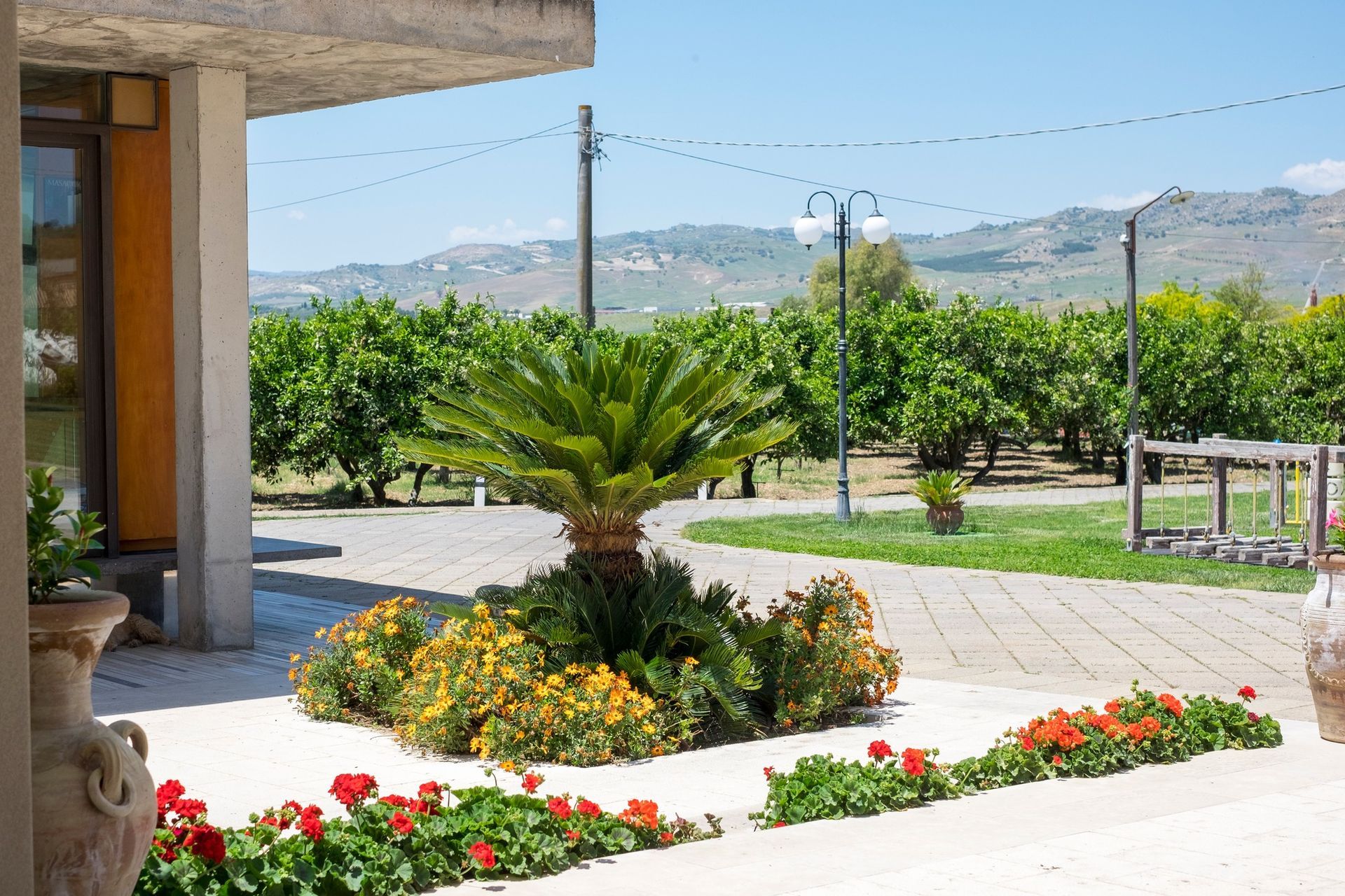 Edificio moderno con palme, un prato verde e un cielo azzurro limpido.