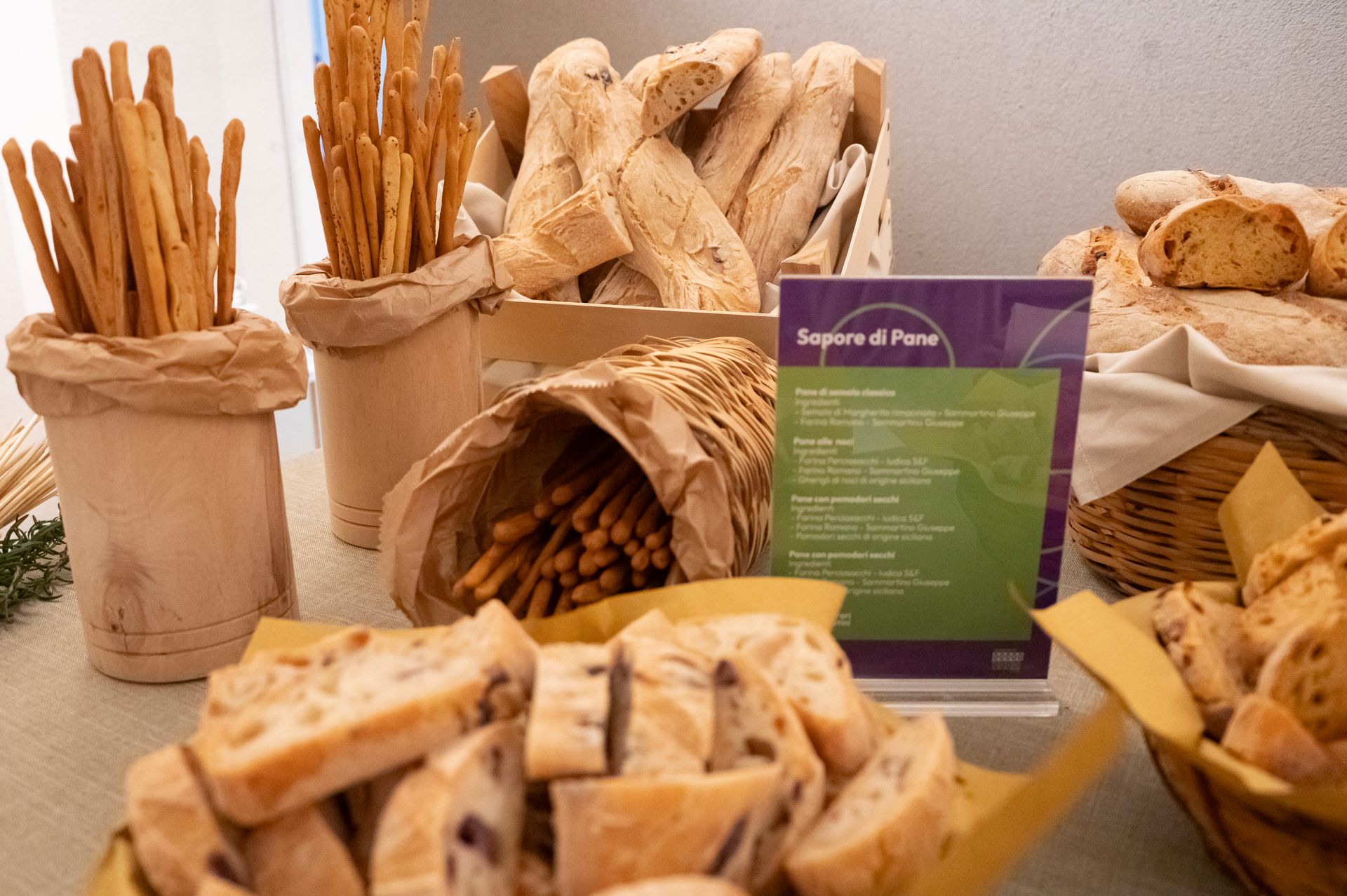 Assortimento di pane e pasticcini esposti su un banco del mercato con un cartello viola