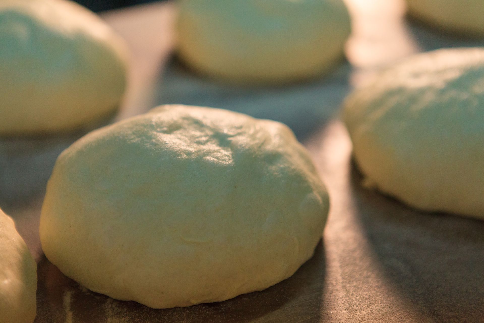 Palline di impasto crudo che lievitano su una teglia in una luce calda