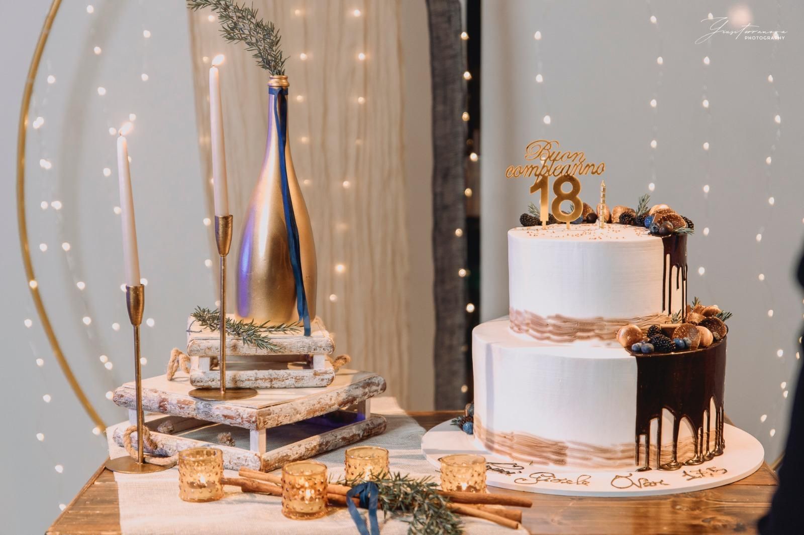 Elegante tavolo da dessert per un compleanno, con torta bianca e oro, cupcake e candeline.